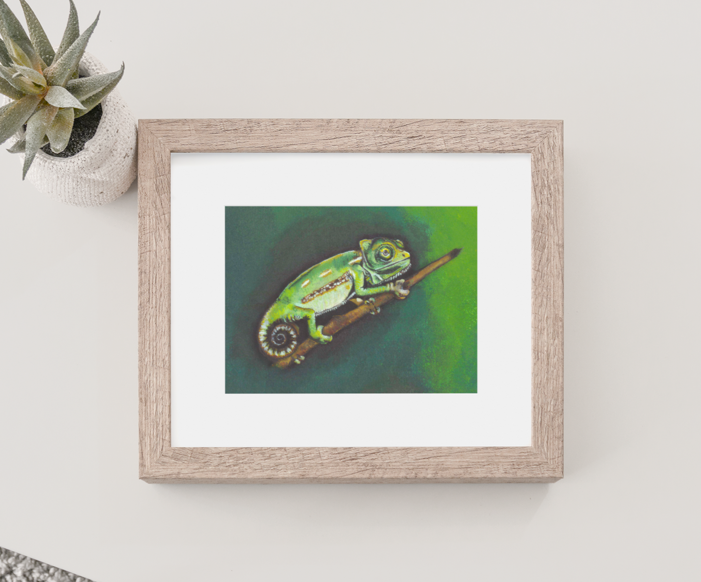 Mock Up of a Baby Yemen Chameleon Art Print (featuring a chameleon on a branch) in a wooden frame. Artwork by Jenny Pond, JPArtwork