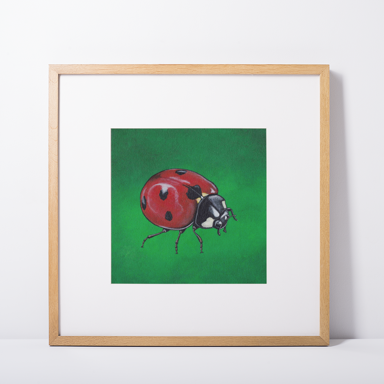 Mock Up of a Ladybird (on a green background) Art Print in a pine square frame. Artwork by Jenny Pond, JPArtwork